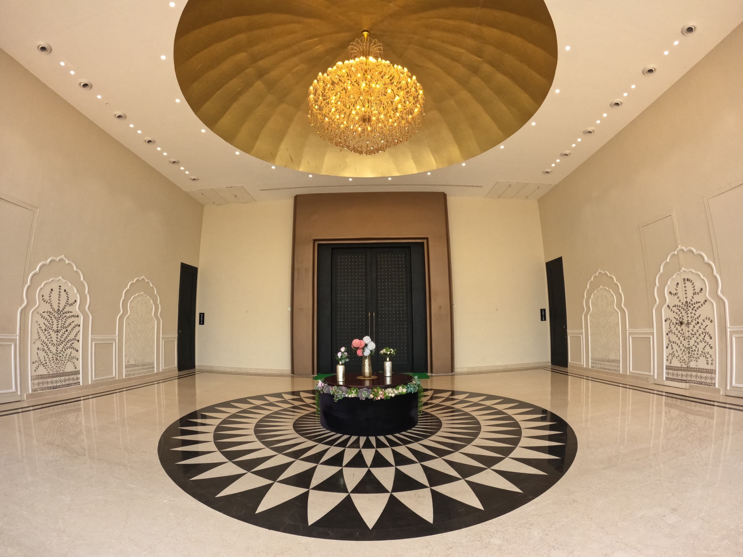 Banquet foyer with a golden domed chandelier and a star-inlaid marble floor